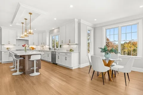 a kitchen with a table chairs wooden floors and a view of living room