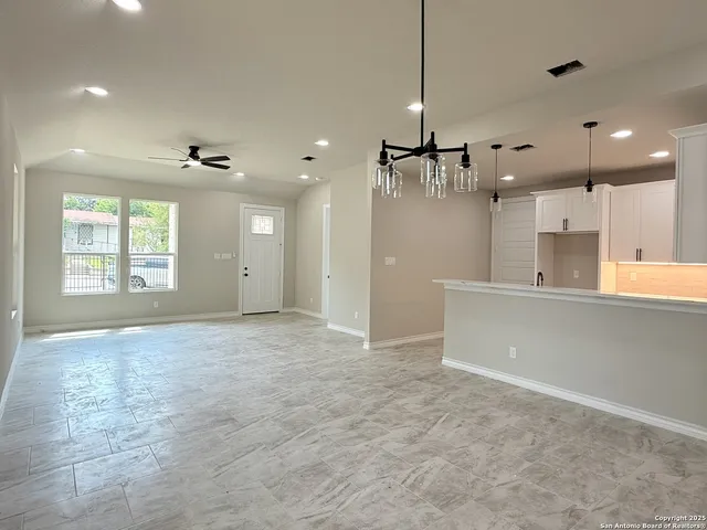 a view of an empty room and a kitchen
