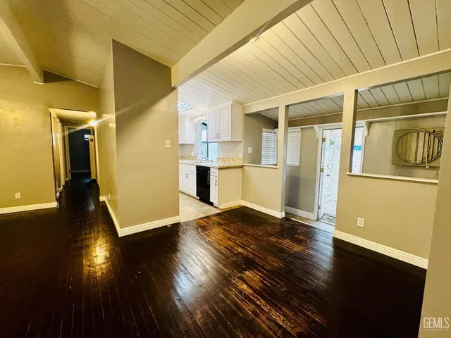 an empty room with wooden floor and windows with curtains