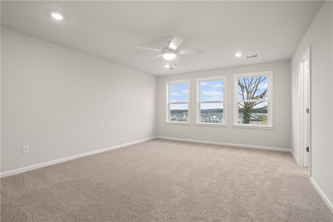 629 Sweetspire Trail, Unit 149 Seneca, SC 29678 - Photo 24 of 30 Three generous windows invite daylight into this comfortable primary bedroom, complemented by a ceiling fan for year-round comfort.