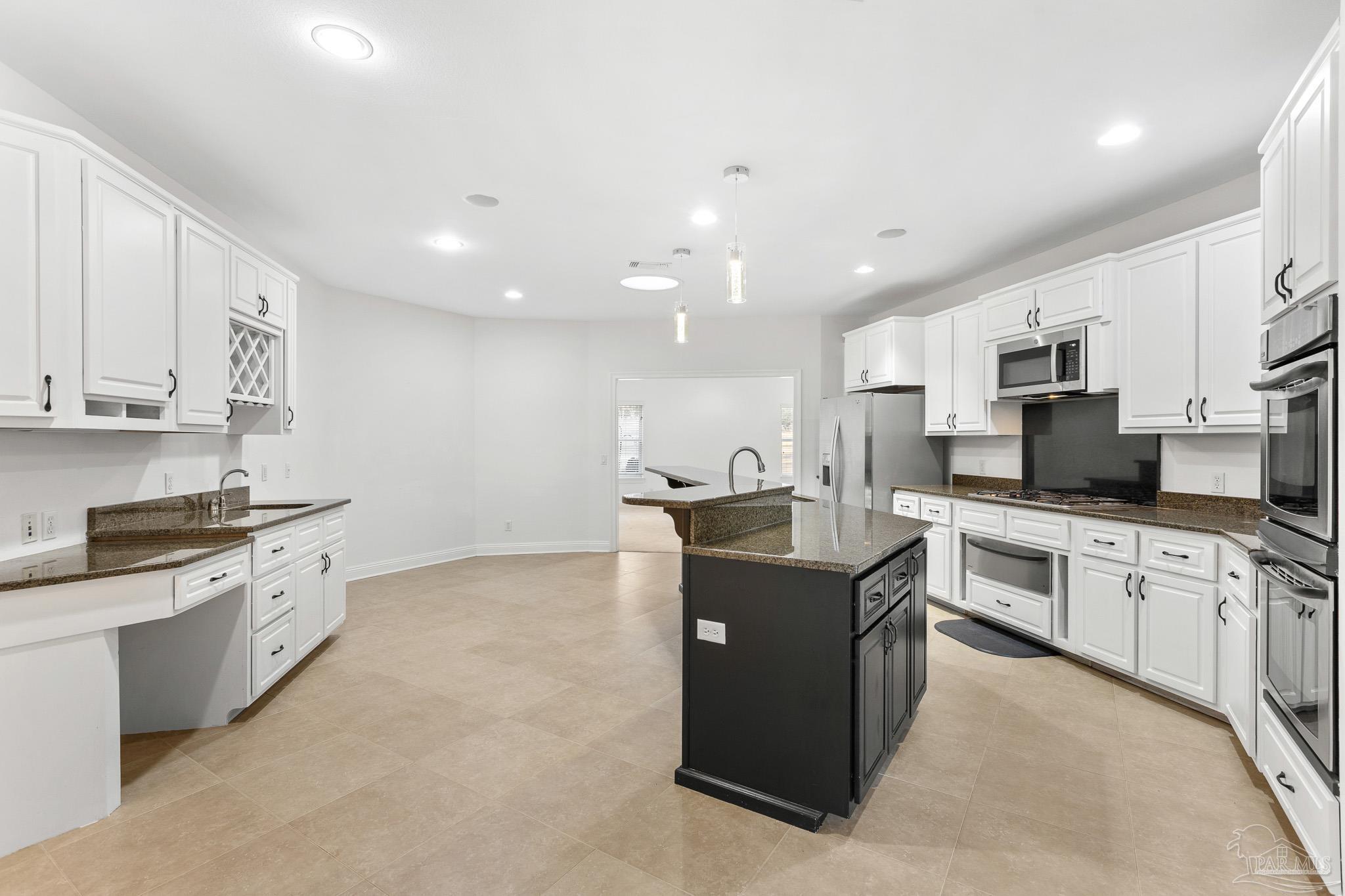 6786 Quintette Road Pace, FL 32571 - Photo 14 of 60 a large kitchen with stainless steel appliances granite countertop a stove top oven a sink and dishwasher with white cabinets