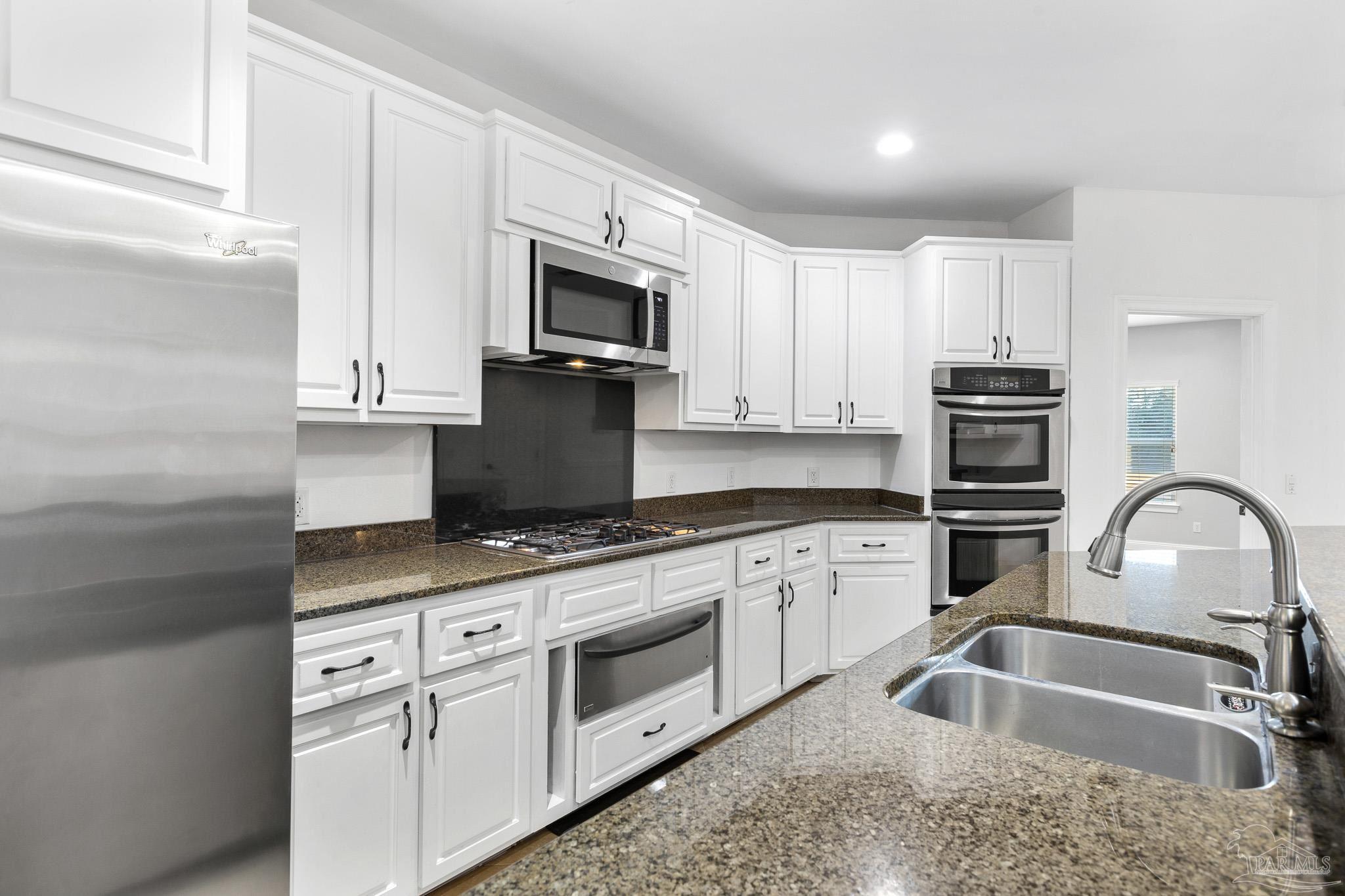 6786 Quintette Road Pace, FL 32571 - Photo 16 of 60 a kitchen with granite countertop a sink stainless steel appliances and white cabinets