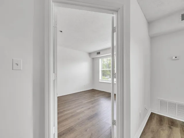 a view of an empty room with wooden floor and a window