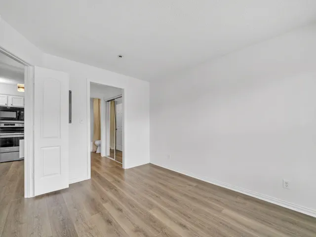 a view of an empty room with wooden floor and closet