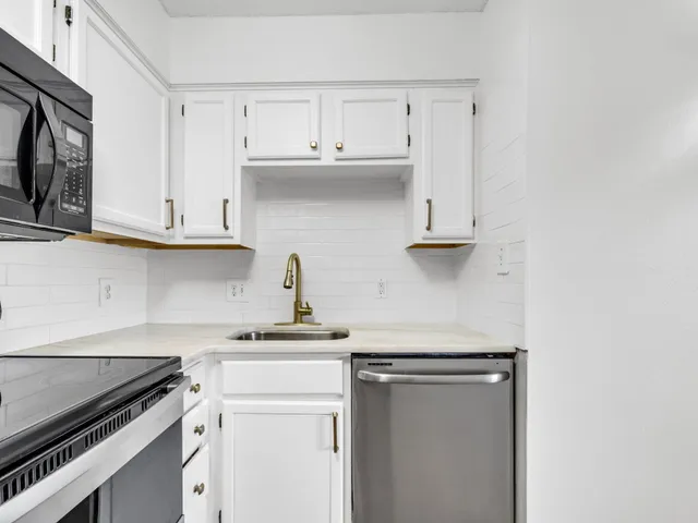 a kitchen with stainless steel appliances granite countertop white cabinets and a stove top oven