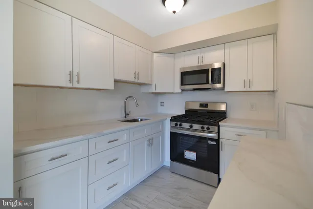 a kitchen with white cabinets and stainless steel appliances