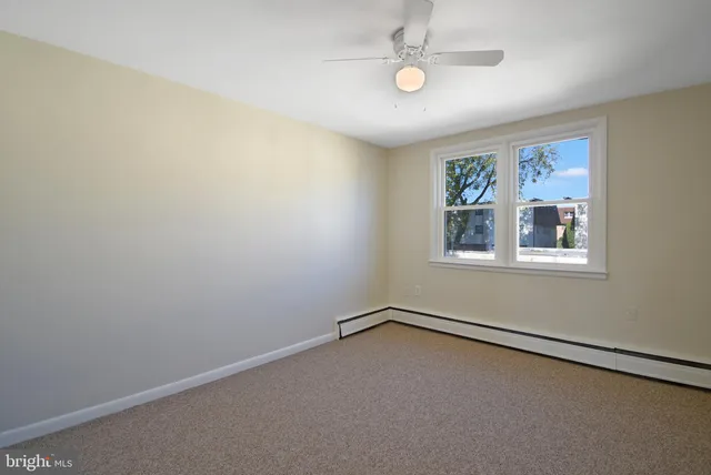 an empty room with windows and ceiling fan