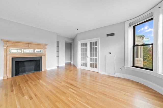 wooden floor fireplace and windows in an empty room