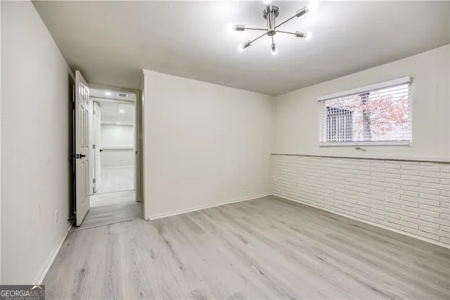 a view of an empty room with wooden floor and a ceiling fan