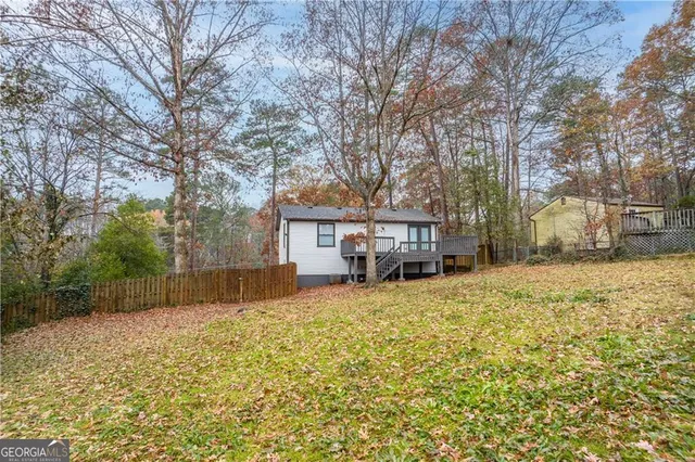 a backyard of a house with large trees and wooden fence