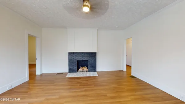 a view of empty room with wooden floor and fireplace