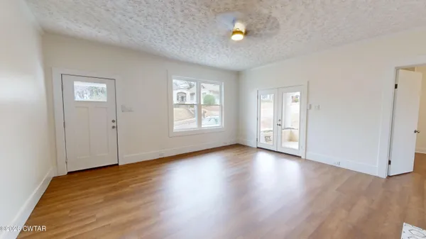 an empty room with wooden floor and windows