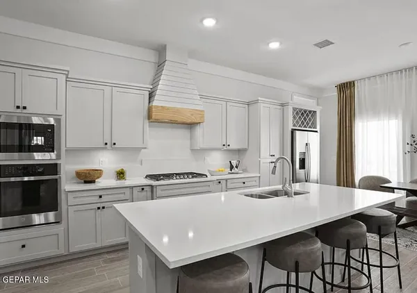 a kitchen with stainless steel appliances a sink a stove a refrigerator cabinets and dining table