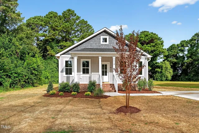 a front view of a house with a yard and potted plants