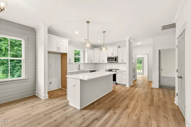 a large kitchen with a center island wooden floor stainless steel appliances and windows
