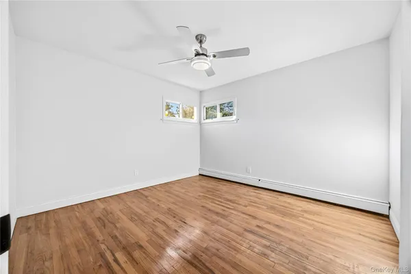 an empty room with a ceiling fan and wooden floor