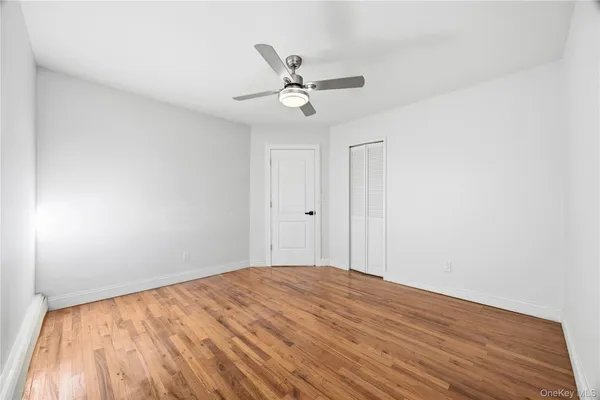a view of empty room with wooden floor and ceiling fan