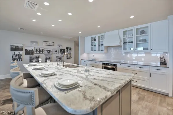 a kitchen with kitchen island granite countertop a sink and white cabinets