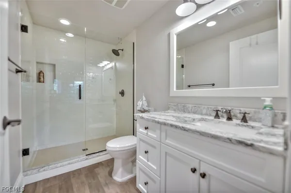 a bathroom with a granite countertop sink toilet and shower