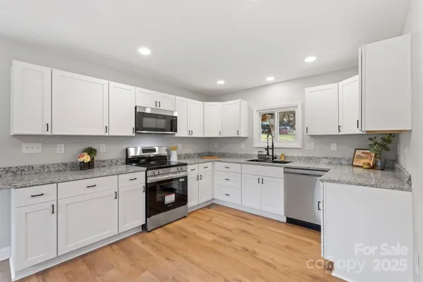 a kitchen with granite countertop white cabinets and stainless steel appliances