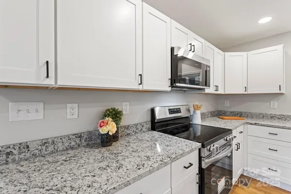 a kitchen with granite countertop white cabinets stainless steel appliances and a sink