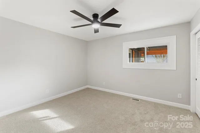 an empty room with a ceiling fan and window