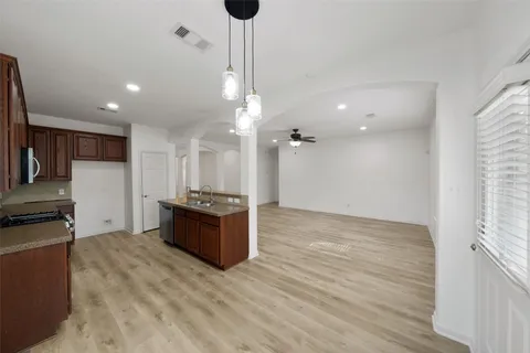 a large kitchen with a large counter top a sink stainless steel appliances and cabinets