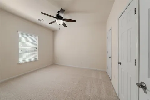 an empty room with a chandelier fan and windows