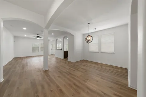 a view of an empty room with wooden floor and windows