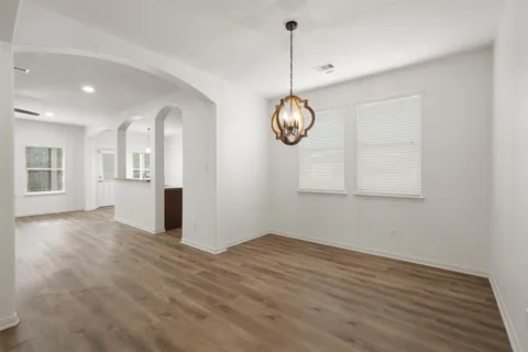 a view of an empty room with window and wooden floor