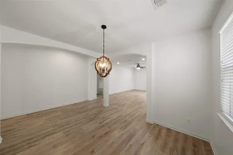 a view of a room with a chandelier fan and wooden floor