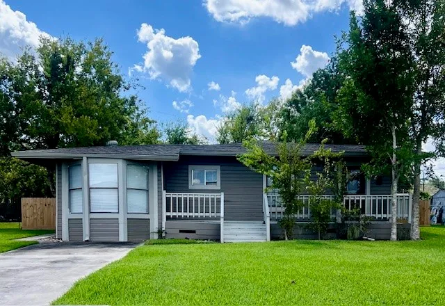 a front view of a house with a garden and trees