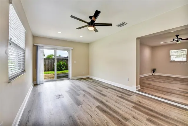 an empty room with wooden floor and windows