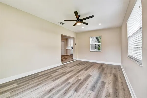 a view of empty room with wooden floor and fan