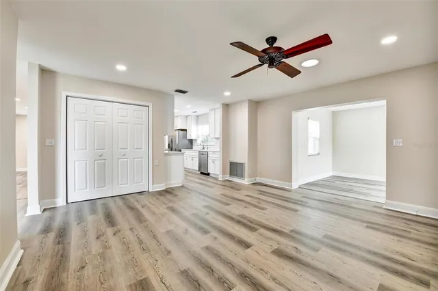 a view of empty room with wooden floor and ceiling fan