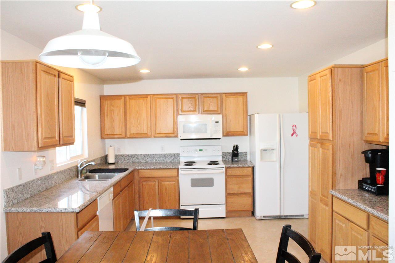 7757 Welsh Drive Reno, NV 89506 - Photo 3 of 23 a kitchen with stainless steel appliances a stove a sink a refrigerator cabinets and a dining table with wooden floor