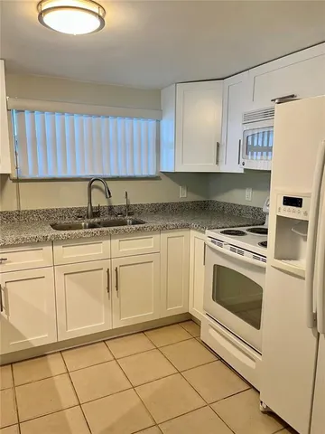 a kitchen with granite countertop a refrigerator and cabinets