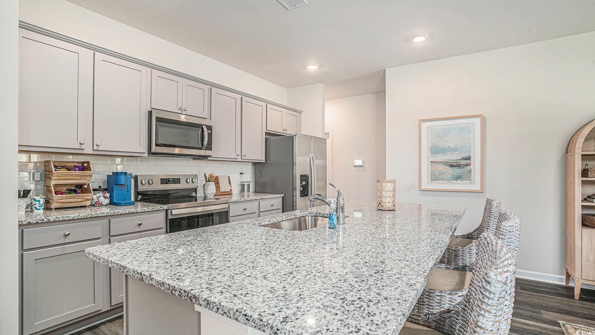 183 Pampa Drive Loris, SC 29569 - Photo 8 of 22 Kitchen featuring stainless steel appliances, light stone countertops, gray cabinetry, a breakfast bar, and a center island with sink