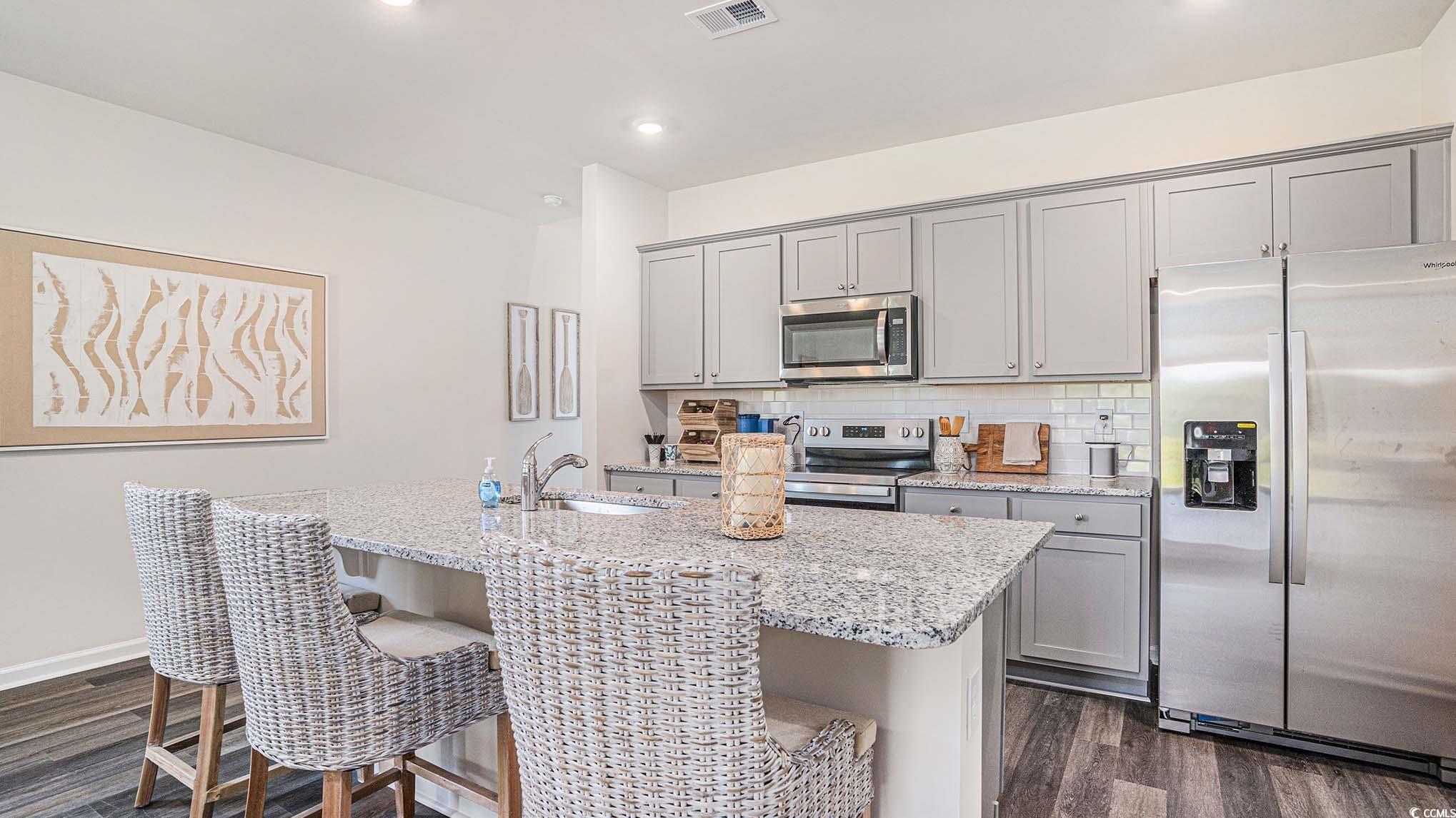 183 Pampa Drive Loris, SC 29569 - Photo 9 of 22 Kitchen featuring gray cabinets, appliances with stainless steel finishes, light stone counters, tasteful backsplash, and dark wood-style floors