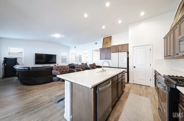 a large kitchen with stainless steel appliances a large counter top and wooden floor