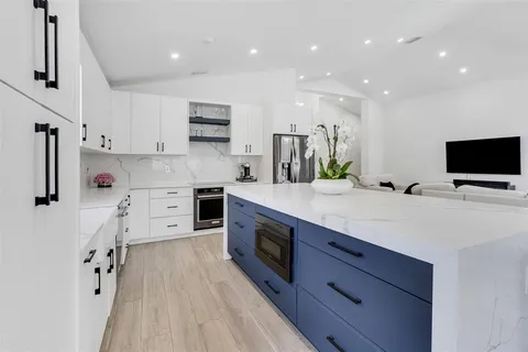 a large kitchen with stainless steel appliances a large counter top a stove a sink and a refrigerator