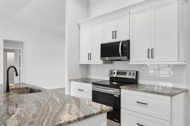 a kitchen with stainless steel appliances granite countertop a sink a stove and a microwave