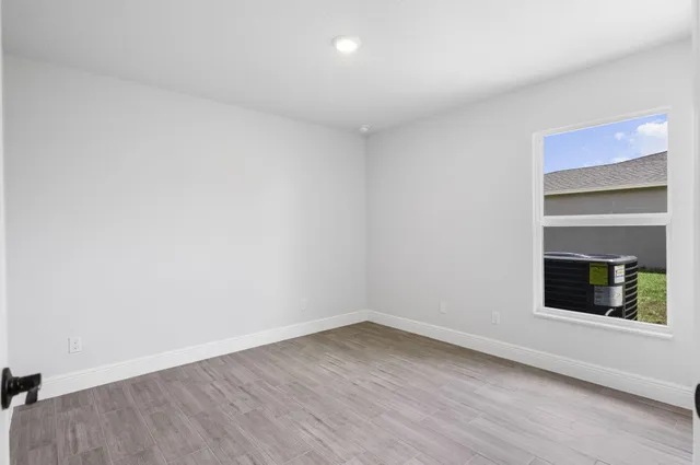 a view of an empty room with a window and wooden floor