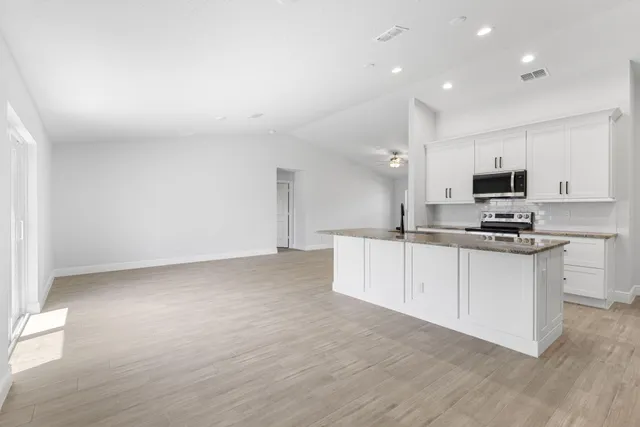 a kitchen with granite countertop a sink cabinets and stainless steel appliances