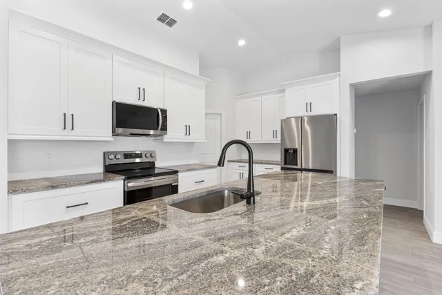 a kitchen with stainless steel appliances granite countertop a refrigerator and a stove top oven