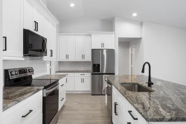 a kitchen with a stove a sink a microwave and refrigerator