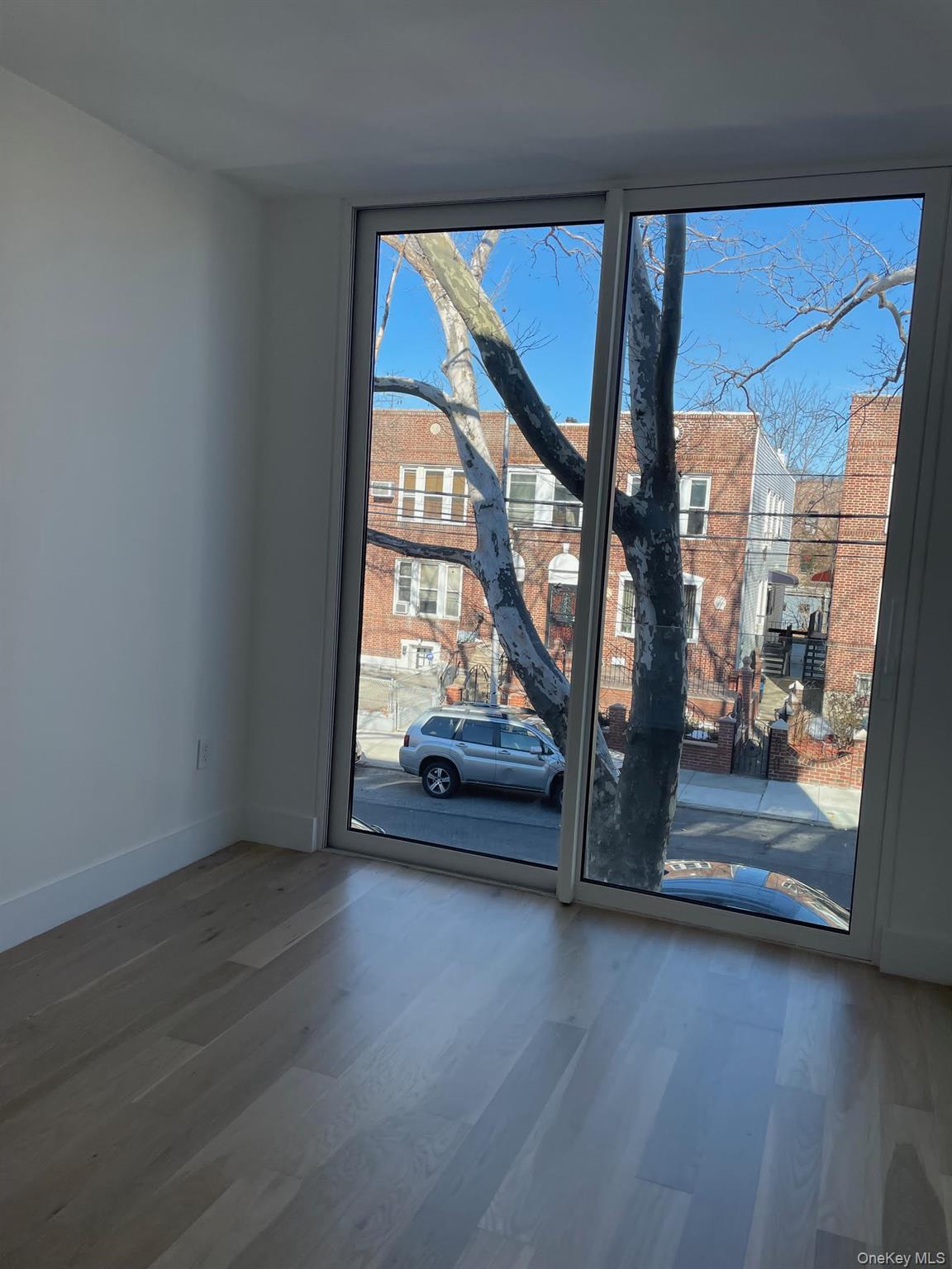 19-14 21st Road, Unit 2A Queens, NY 11105 - Photo 13 of 19 a view of an empty room with wooden floor and a window
