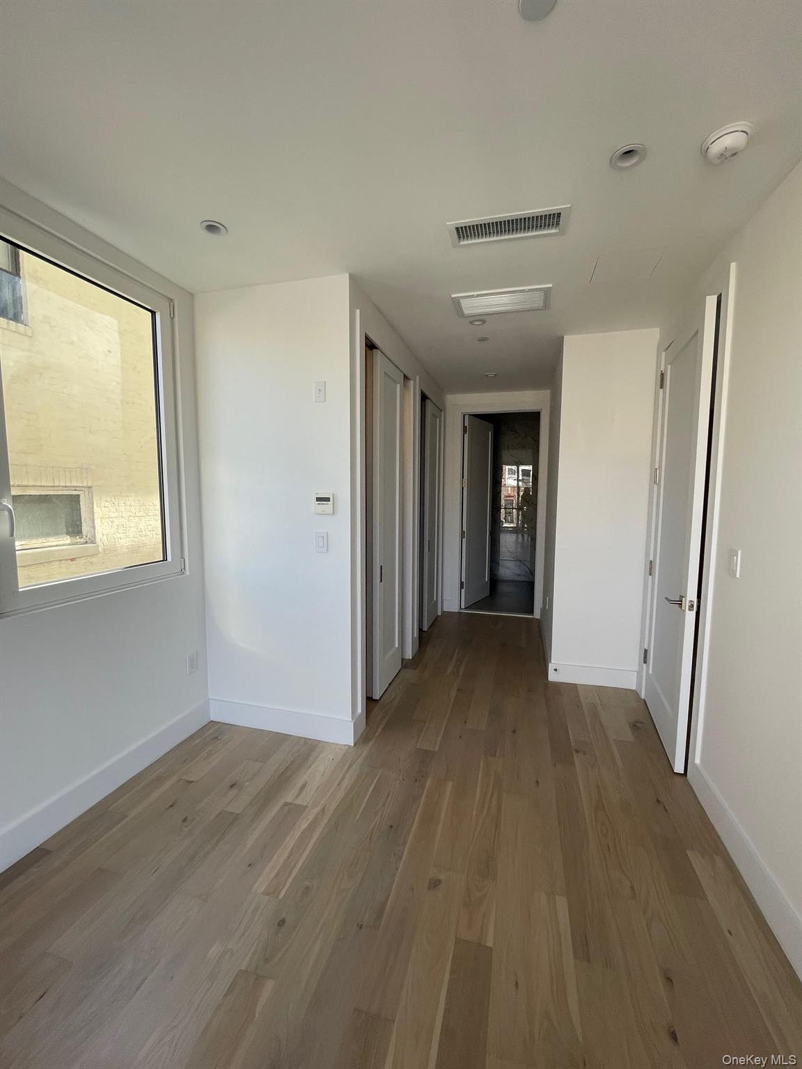 19-14 21st Road, Unit 2A Queens, NY 11105 - Photo 2 of 19 an empty room with wooden floor and windows
