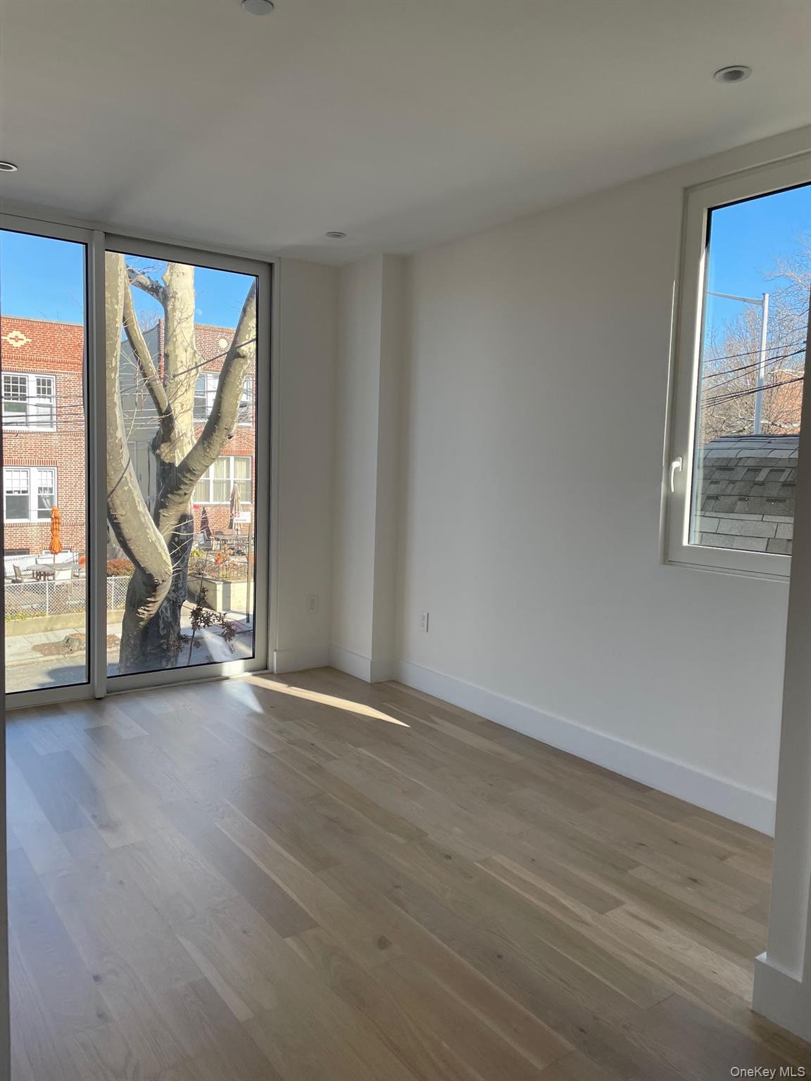 19-14 21st Road, Unit 2A Queens, NY 11105 - Photo 6 of 19 a view of an empty room with wooden floor and a window