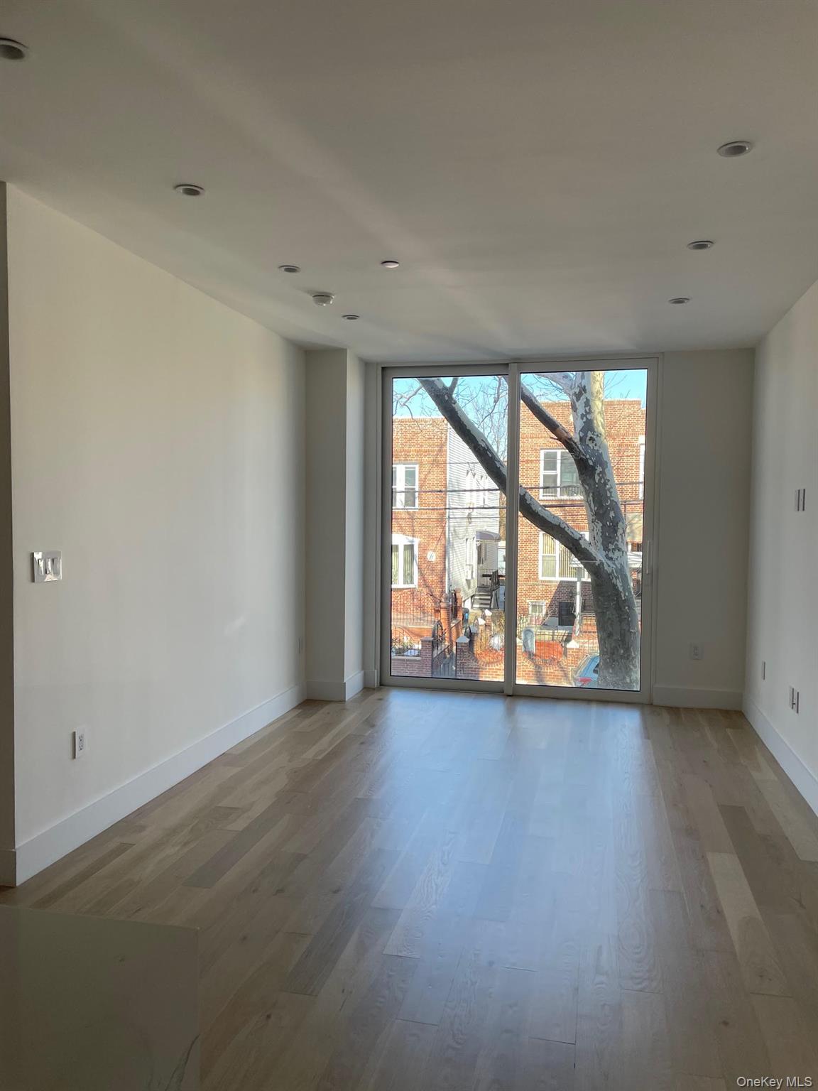 19-14 21st Road, Unit 2A Queens, NY 11105 - Photo 8 of 19 an empty room with wooden floor and windows